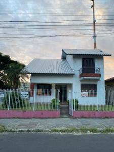 a white house with a fence in front of it at Casa para Pernoite no Centro de Osório in Osório +2 photos