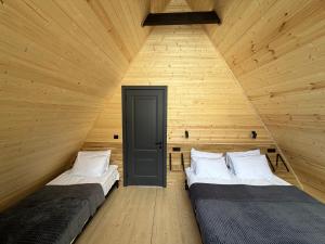 twee bedden in een kamer met houten wanden en een deur bij Kazbegi Story in Kazbegi