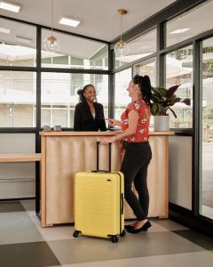 twee vrouwen aan een balie met een gele koffer bij Colony House Motor Lodge in Roanoke +30 foto's