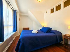 a bedroom with a blue bed with towels on it at La Galería B&B in Valparaíso