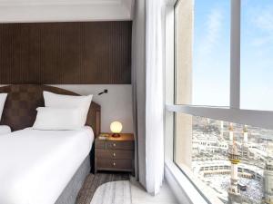 a bedroom with a bed and a large window at Zamzam Pullman Makkah in Mecca