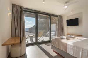 a bedroom with a bed and a balcony with a television at Avera Villas in Parikia +190 photos