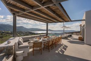 een terras met een bank, tafels en stoelen bij Avera Villas in Parikia