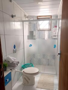 een witte badkamer met toilet en douche bij Casa Rústica em Garopaba in Garopaba