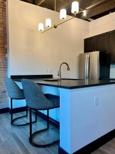 a kitchen with a counter with two chairs and a sink at Brick & Bed Riverfront Lofts, T 302 in Saint Louis +4 photos