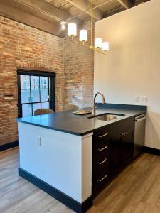 a kitchen with a sink and a brick wall at Brick & Bed Riverfront Lofts, T 302 in Saint Louis
