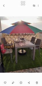 a picnic table with an umbrella on the grass at F3 vue sur le mere in Mostaganem