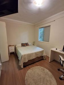 una camera da letto con un letto, una scrivania e una finestra di Jasmim 12 a Santo André
