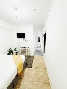 a bedroom with white walls and a bed and a desk at Stylish 2-Guest Studio with Netflix, Prime - FREE WIFI & FREE PARKING - Aroluchi Ville in Ecclesfield