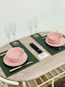 a table with two pink plates and wine glasses at Stylish 2-Guest Studio with Netflix, Prime - FREE WIFI & FREE PARKING - Aroluchi Ville in Ecclesfield