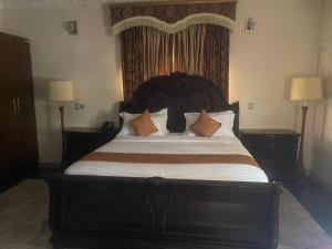 a large bed in a bedroom with two lamps at GALLANISUITES hotels in Ibadan