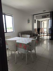 een woonkamer met een tafel, stoelen en een bank bij Pajuçara Maceio Pé na Areia in Maceió