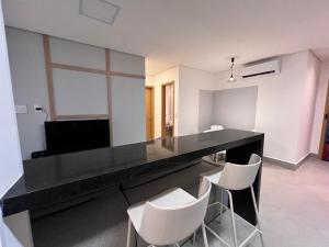 a large black counter with white chairs in a room at Aptos em Prédio com Piscina e Academia - GRL in Anápolis
