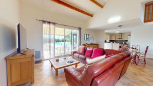 a living room with a leather couch and a television at Villa BlueGreen in Coëx
