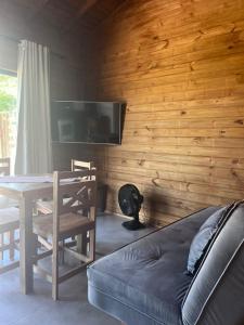een woonkamer met een houten muur met een tafel en een bank bij Residencial Bambu in Garopaba