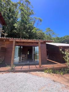 een houten hut met een veranda en een patio bij Residencial Bambu in Garopaba