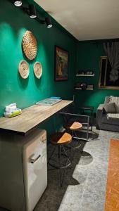 une cuisine avec un mur vert, un comptoir et des tabourets dans l'établissement Mango Haus, à Aqaba