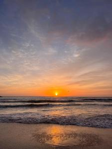 een zonsondergang op een strand met de oceaan bij Residencial Bambu in Garopaba +1 foto