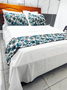 a white bed with blue and white sheets and pillows at Résidence meuble in Abidjan