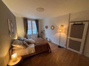 een slaapkamer met een bed, een lamp en een raam bij Gîte du Palais 3 étoiles in Châteauneuf-sur-Cher