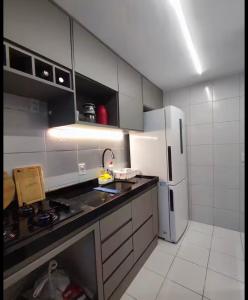 una cucina con mobili bianchi e un frigorifero bianco di Ótima localização 20 min Pajucara a Maceió