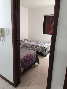 een kamer met 2 bedden en een spiegel bij Pajuçara Maceio Pé na Areia in Maceió