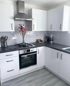 een witte keuken met een fornuis en een vaas met bloemen bij kusum properties in Trofwi