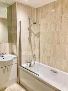 a bathroom with a shower and a tub and a sink at VIPAbodes at Woking Central in Woking