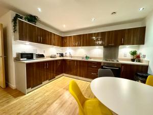 een keuken met houten kasten en een tafel met gele stoelen bij VIPAbodes at Woking Central in Woking