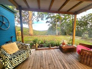 eine Veranda mit einem Sofa und einem Tisch auf einer Terrasse in der Unterkunft Blue Horizon, Couple's GC Hinterland retreat in Tallebudgera + 16 Fotos