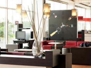 een lobby met een vaas op een tafel met rode stoelen bij Ibis Aguascalientes Norte in Aguascalientes