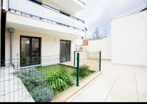 a courtyard of a house with a fence and plants at Paris sud studio cosy in Arcueil +3 photos