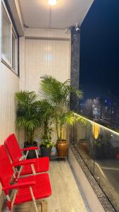 a row of red chairs on a balcony with plants at NIVAASe STAYS in New Delhi