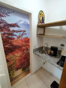 a kitchen with a painting of a mountain on the wall at Kitnet no Morro dos Conventos in Araranguá