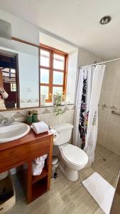 a bathroom with a toilet and a sink and a mirror at Casa Munay in Urubamba
