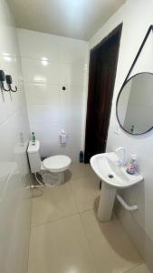 une salle de bains blanche avec toilettes et lavabo dans l'établissement Kit net em Penedo l perto do centro turístico, à Itatiaia
