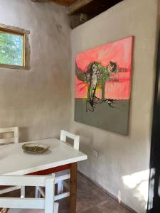 een schilderij van een vogel op een muur naast een tafel bij Icho's mud house in Villa Icho Cruz