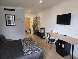 a bedroom with a bed and a desk in a room at Charbonnier Motor Inn in Singleton