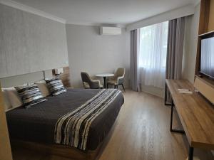 a hotel room with a bed and a table with chairs at Charbonnier Motor Inn in Singleton +48 photos
