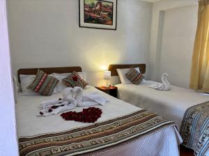 two beds in a room with towels and flowers on them at Tambo Real Valle Sagrado in Yucay