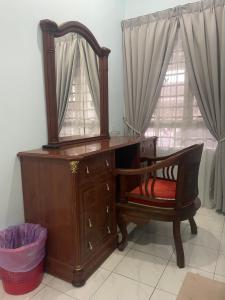 a wooden dresser with a mirror and a chair at Roma Guesthouse Terrace With 3 Bedroom & Airconditioning in Shah Alam
