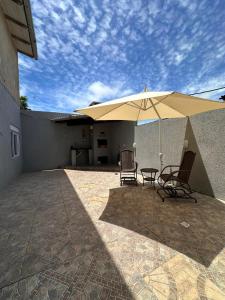a patio with two chairs and an umbrella at Apartamento Amplo em Tramandaí in Tramandaí