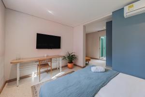 een slaapkamer met een bed en een bureau met een televisie bij Medellinn The Blooming Hotel in Medellín