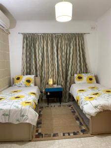 a bedroom with two beds and a window with sunflowers at Adinkra Suits in Ħal Balzan