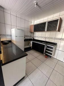 a kitchen with white appliances and black counter tops at Apartamento Amplo em Tramandaí in Tramandaí