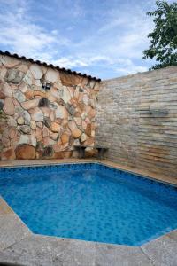 a swimming pool in front of a stone wall at Cantinho Abençoado in Pirenópolis