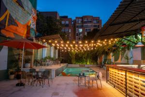een terras met een zwembad, tafels, stoelen en verlichting bij Medellinn The Blooming Hotel in Medellín