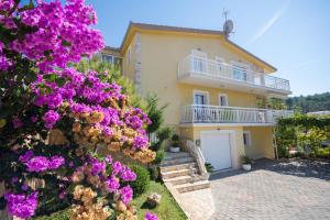 una casa con flores púrpuras delante de ella en Apartments Kapetan, en Trogir
