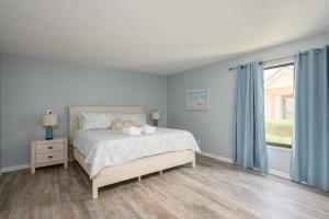 een witte slaapkamer met een bed en een raam bij Queens Grant Unit 751 in Hilton Head Island +5 foto's
