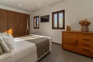 a bedroom with a bed and a wooden dresser at Lindos 4 me Villa in Lindos +18 photos